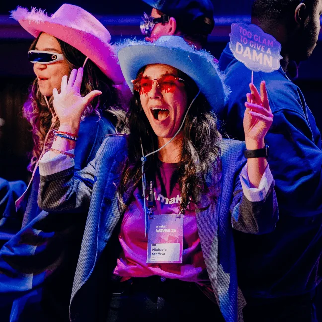 Two guests in pink hats laughing at a previous Waves party