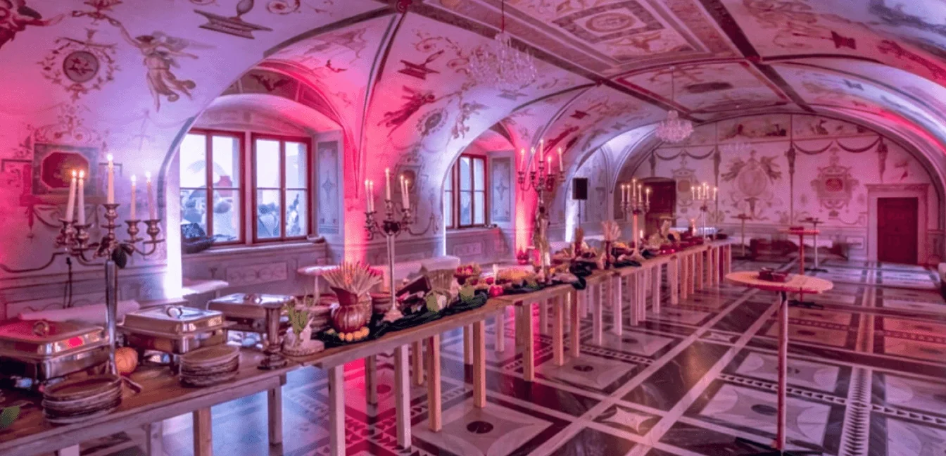 The vaulted hall of Martinický Palace lit pink, set for dinner